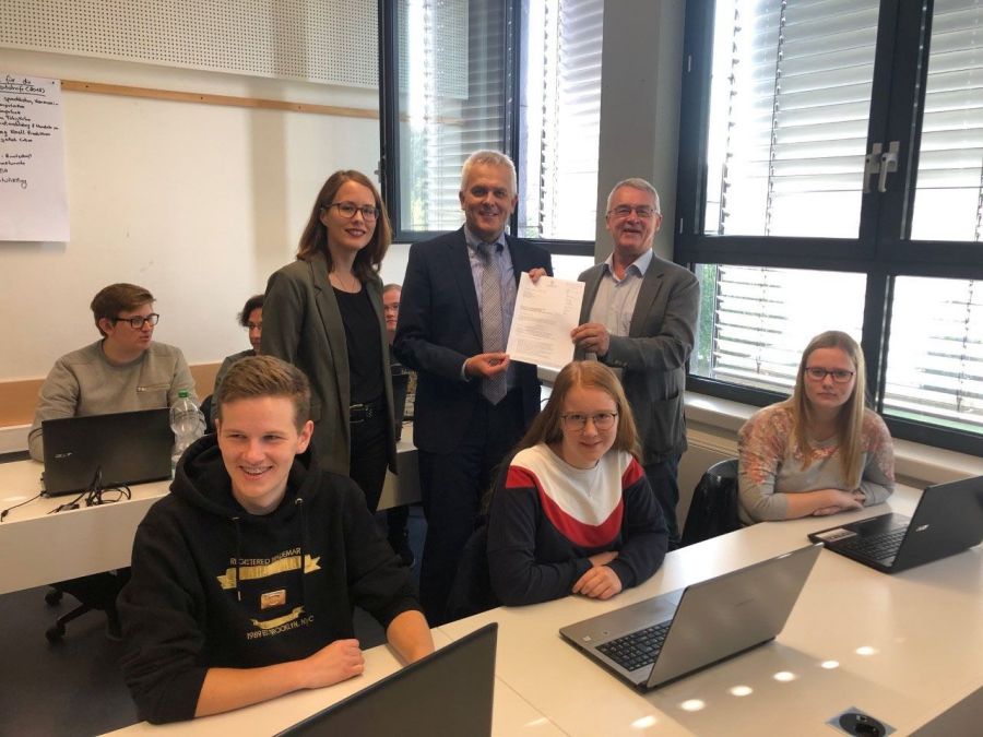 Auf dem vom Berufskolleg Schloß Neuhaus zur Verfügung gestellten Foto sind vorne von links nach rechts folgende Schüler aus dem Beruflichen Gymnasium zu sehen: Daniel Zerr, Lisa Grenner, Janina Brunnert. Dahinter stehen: Marie-Ann Kückmann, Wissenschaftliche Mitarbeiterin an der Professur für Wirtschaftspädagogik, insb. Mediendidaktik und Weiterbildung der Universität Paderborn, in der Mitte der Schulleiter des Berufskolleg Schloß Neuhaus, Matthias Groß und rechts  Dr. Burghard Lehmann, Geschäftsführer der Osthushenrich-Stiftung